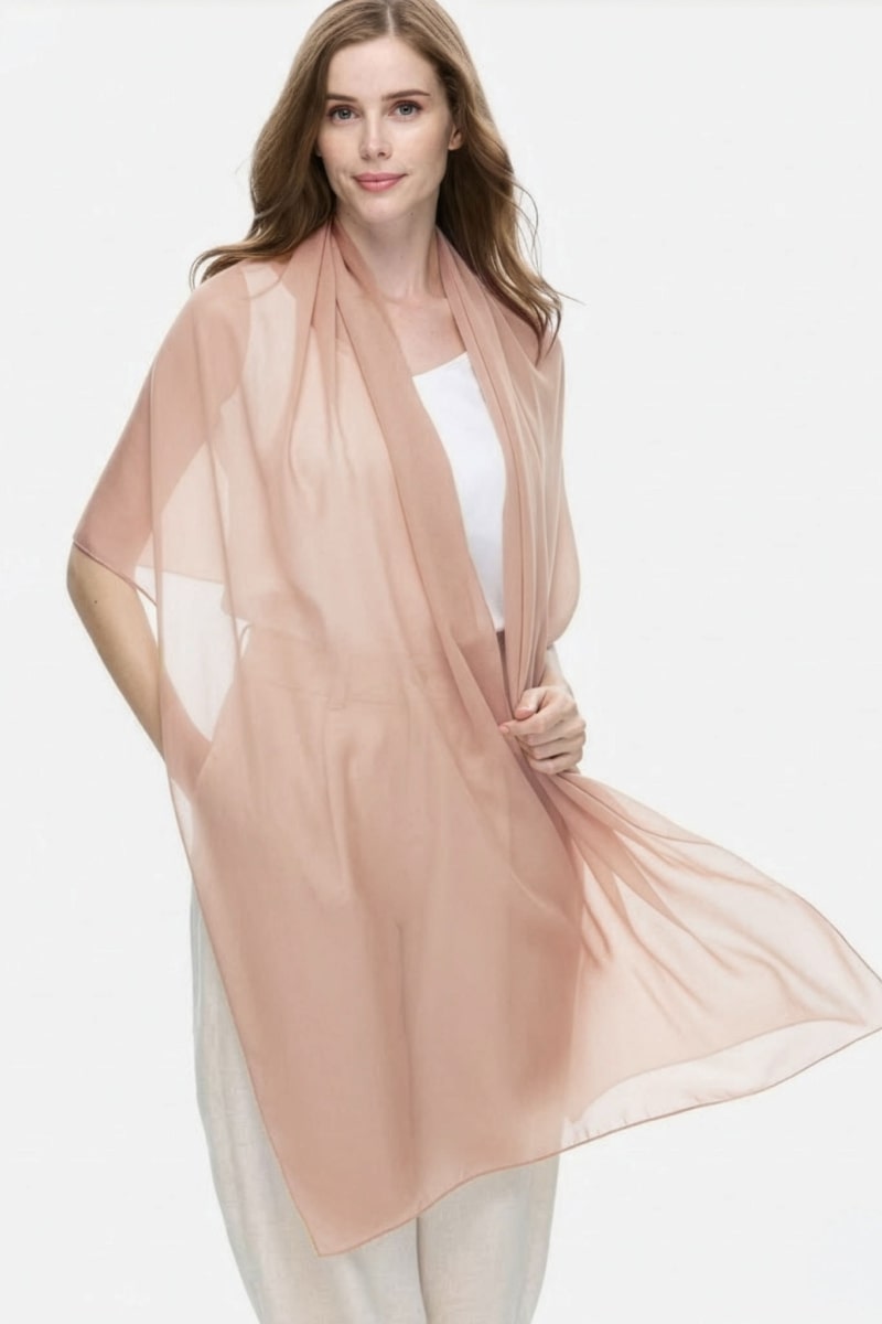 A woman wears the looselyboho Sandstone Dune 100% Cashmere Scarf over a white top and light pants, standing against a plain white background and looking at the camera with a neutral expression.