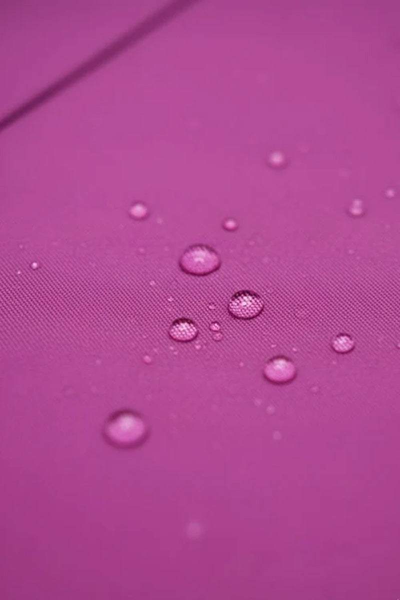 Close-up of water droplets on smooth pink fabric highlights the water-repellent design of the looselyboho Water-Repellent Rain & Shine A-Line Hooded Raincoat—a stylish women’s coat for staying dry in any weather.