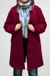 A model showcases the looselyboho BURGUNDY BLOSSOM WINDBREAKER with a floral lining, paired with a blue pastel scarf and jeans. They pull its sides adorned with black buttons and elastic cuffs, while the water-resistant fabric stands out against a plain white backdrop.