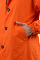 A person wearing the Icon Windbreaker Rain Jacket with black buttons puts their right hand in the side pocket. Only the torso and hand are shown.