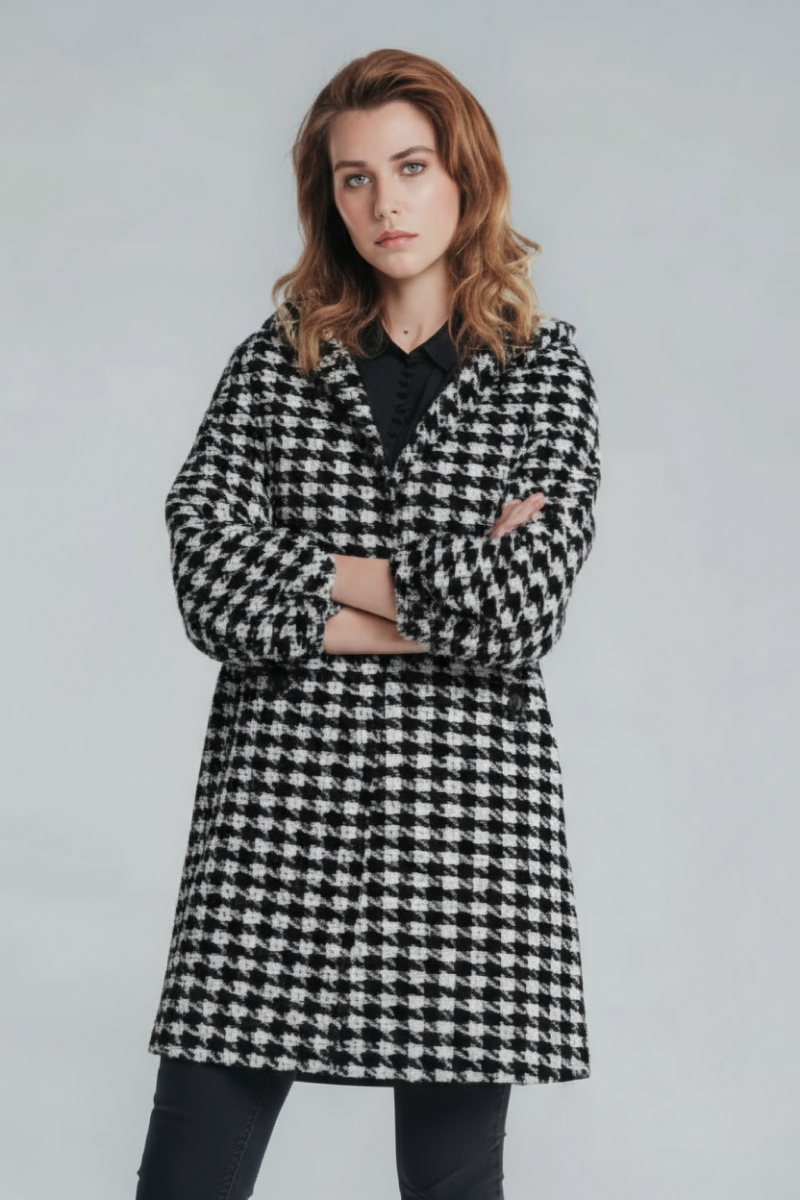 A woman with shoulder-length brown hair stands with arms crossed, modeling the looselyboho HOUNDSTOOTH WINDBREAKER over dark pants and a black top, against a plain light gray background.