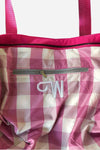 The One" Barbara Pink Waterproof Travel Bag by looselyboho, crafted from lightweight pink and white checkered fabric. It features a central zippered pocket with a grey zipper and reinforced pink handles. The embroidered white "CW" monogram beneath the pocket adds both style and functionality to this versatile accessory.