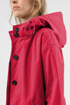 Side profile of a person wearing a bright red VIVA MAGENTA WINDBREAKER from looselyboho with black buttons, ideal for outdoor activities. The image focuses on the upper half of the water-resistant jacket, showcasing its details, including drawstrings on the hood and intricate stitching on the shoulder and collar. The background is plain white.