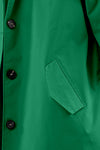 Close-up of an EMERALD GREEN WINDBREAKER by The Windbreaker Jacket featuring black buttons, a single welt pocket on the left side, and an adjustable hood. The fabric appears smooth and slightly shiny, indicating a stylish and possibly water-resistant material.